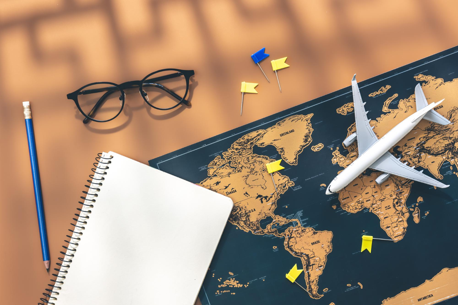 Un cahier miniature, un avion et une carte du monde sur fond marron